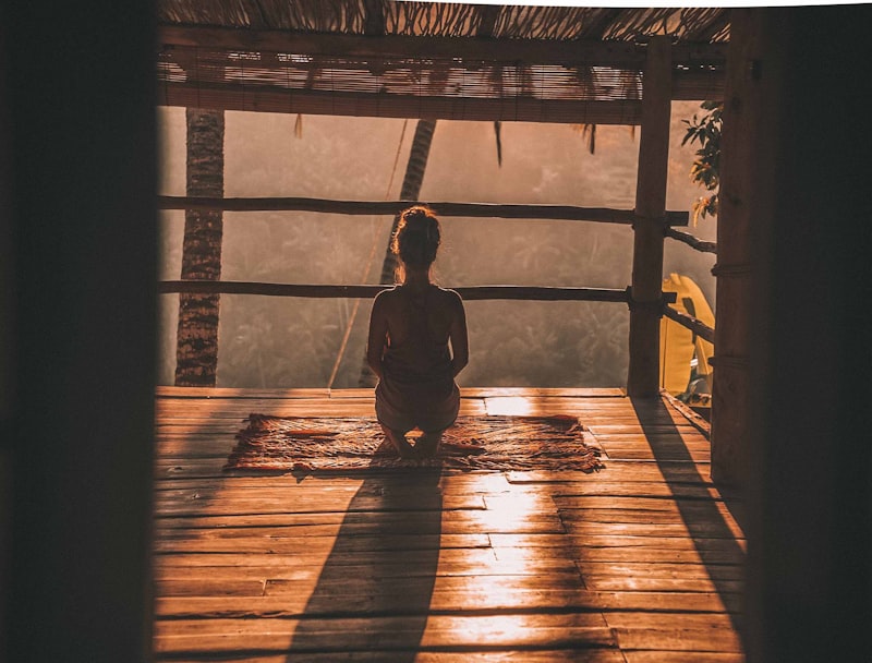 Woman practising morning yoga meditation overlooking a lush jungle at sunrise
